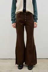 Pantalón de denim tiro alto con corte oxford y tajos laterales en el ruedo. Presenta cierre frontal con botones a la vista y costuras verticales decorativas.