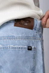 Jean de corte mom oversize, color negro lavado, con diseño de cinco bolsillos y cierre frontal con botón y cremallera.