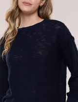 Buzo liviano de algodón con tejido de punto abierto y semi holgado, color beige, con escote bote, mangas largas de hombros caídos y costuras expuestas.
