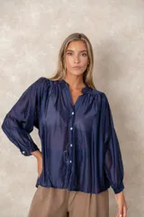Camisa de organza blanca con cuello mao, diseño de manga larga tipo murciélago y cierre frontal con botones. Presenta un corte holgado y fluido.