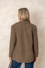 Blazer de corte sastre con diseño de espiga en tonos grises. Presenta un bordado floral lineal en el lateral, solapas clásicas, cierre frontal con un botón y bolsillos con solapa.