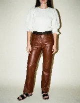 Pantalón de cuero vacuno color marrón, de corte recto y tiro medio. Presenta una cintura con detalle de presillas fruncidas en contraste negro y forrería interna de satén.