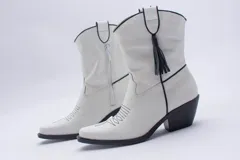 Botas estilo texanas de caña media, confeccionadas en cuero con estampado animal print tipo vaca en blanco y negro. Presentan un diseño de punta fina y taco cuadrado.
