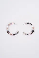 Aros tipo argolla de gran tamaño, decorados con una combinación de cuentas de disco de colores neutros, perlas sintéticas, cuentas de cristal y dijes irregulares.