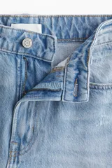 Bermuda de cinco bolsillos en denim de algodón rígido, corte holgado con cierre y botón, lavado claro y detalles de roturas.