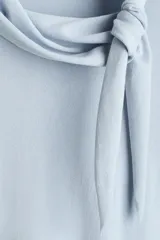 Buzo en punto fino de mezcla de viscosa color celeste, modelo entallado con cuello pañuelo integrado y remate acanalado en puños y bajo.