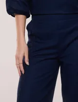 Pantalón crop de lino y algodón color blanco, con calce holgado, pierna ancha de corte recto y cintura elástica. Presenta bolsillos laterales y detalle de puntilla aplicada en el frente.