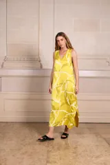 Vestido largo de seda color amarillo con estampado batik en tonos verde oliva y blanco. Escote en V con ribete de punto fino en cuello y mangas. Talle único.