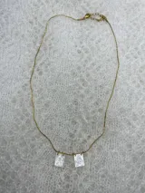 Collar dorado con cadena fina y dos dijes rectangulares con imágenes religiosas.