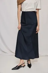 Falda larga de color negro, calce al cuerpo y caída fluida, confeccionada en tejido satinado con detalle de recorte diagonal en la parte delantera y cintura elástica.