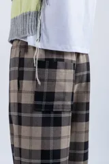 Pantalón de vestir con corte recto y tiro medio, con cintura elástica y bolsillos laterales. Diseño a cuadros en tonos marrón, beige y negro.
