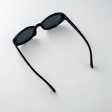 Lentes de sol con armazón ovalado de carey y micas marrones, con detalle metálico dorado en las esquinas y patillas.