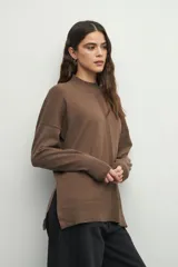 Polera color beige de manga larga con puños elastizados y aberturas laterales.