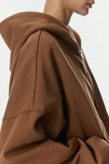 Campera con capucha de corte holgado y diseño cropped, confeccionada en felpa con interior cepillado. Presenta cierre frontal, hombros caídos, bolsillos tipo parche y terminaciones en punto acanalado en puños y bajo.
