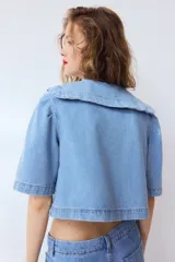Blusa corta de denim de algodón con cuello Peter Pan bordado, mangas cortas abullonadas y cierre frontal con botones.