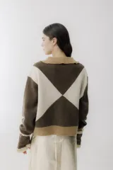 Chaqueta bomber azul marino con paneles color mostaza en forma de rombos. Tiene cuello tipo camisa, cierre frontal con cremallera, bolsillos de parche y puños y bajo acanalados en color marrón.