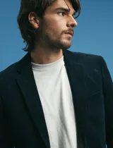 Saco sport de pana color marrón, con cuello de solapa, cierre frontal de dos botones, bolsillos laterales con tapa y puños con botones.