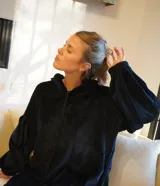 Buzo tipo canguro oversize de plush color negro, con capucha, cierre frontal y mangas abullonadas.