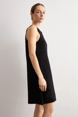 Vestido corto negro sin mangas, de corte recto y escote redondo, con detalles de tejido calado en el ruedo.