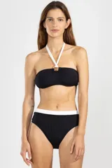Top de bikini negro con textura acanalada, corte bandeau, tirantes blancos y aro decorativo en el centro.