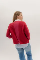 Buzo de punto en color negro con mangas tres cuartos y puños en contraste color marrón. Presenta un diseño holgado con tajos laterales y un aplique circular con logo en la parte inferior.