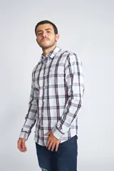 Camisa de manga larga con estampado de cuadros en tonos blanco, celeste y azul marino, con detalles en rosa. Presenta cuello clásico, cierre frontal con botones y logo bordado en el pecho.