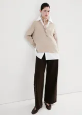 Sweater de punto color beige con cuello en V y mangas largas, diseño holgado.