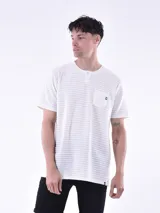 Remera blanca a rayas horizontales grises, con cuello redondo abotonado y bolsillo en el pecho.