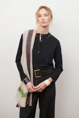 Remera de manga larga color negro, con cuello redondo y cierre frontal parcial con botones. Confeccionada en tejido de punto suave.