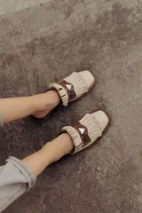 Zueco de cuero color crudo, con diseño destalonado, punta cuadrada, detalle de flecos y una pieza central de cuero con estampado snake en tonos marrones y un aplique metálico triangular.