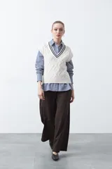 Chaleco de punto color bordó, con diseño de rombos y trenzas en relieve. Escote en V con ribete blanco y rojo.