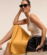 Pollera midi evasé de color beige claro, confeccionada en tela satinada de poliéster.