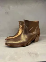 Botas cortas de cuero color bronce con puntera fina, detalle de costuras en el empeine y taco de madera.