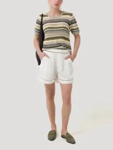Remera de tejido calado a rayas horizontales en tonos beige, marrón, verde y gris. Tiene cuello redondo con borde ondulado y mangas cortas con borde ondulado.