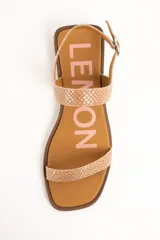 Sandalias planas de cuero color beige con estampado tipo animal print de serpiente texturado. Posee una tira delgada en la parte delantera y una tira ajustable con hebilla metálica alrededor del tobillo, sobre una suela plana y punta cuadrada.