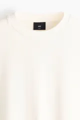 Remera de algodón pesado color blanco con cuello redondo acanalado, hombros caídos y corte holgado de silueta boxy.