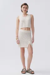 Falda corta de tejido calado color crudo con cintura elastizada y cordones laterales.