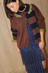 Cardigan de tejido de punto con diseño a rayas horizontales en tonos marrón y azul marino. Presenta cierre frontal con doble cursor, cuello tipo polo con detalles en hilo metalizado dorado y puños con el mismo acabado brillante.
