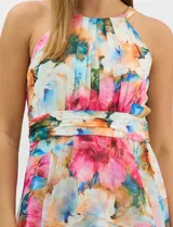 Vestido largo de chifón con estampado floral multicolor. Presenta cuello halter con plisado en el pecho, cintura drapeada y falda amplia con capas asimétricas que aportan movimiento. Incluye forro interior y cierre invisible en la espalda.