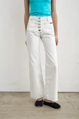 Jeans de denim blanco de tiro alto, corte recto y amplios bolsillos frontales aplicados. Cuenta con cierre frontal abotonado con múltiples botones metálicos a la vista y pespuntes en contraste.