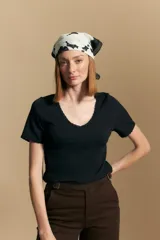 Remera de manga corta en tejido acanalado, con escote en V y detalles de puntilla en el borde del escote y en las mangas. Presenta un ajuste entallado al cuerpo.