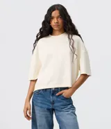 Remera de modal color crudo, con diseño minimalista, calce amplio, cuello redondo y mangas cortas amplias con hombros caídos.
