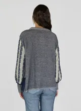 Sweater de punto con diseño de rayas verticales en tonos beige y azul marino, con textura trenzada, cuello redondo, mangas largas y aberturas laterales en el ruedo.