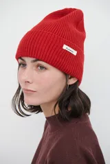 Gorro beanie de punto rib color rojo con vuelta y pequeña etiqueta blanca con la inscripción "Autumn" en el lateral.