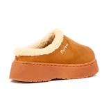 Pantufla tipo zueco de gamuza color camel, con interior forrado en corderito sintético color crema y suela de plataforma plana.