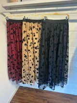 Falda larga de tul en color canela con bordados de flores negras. Presenta una silueta amplia y fluida, ideal para eventos formales.