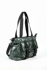 Cartera tipo tote bag color verde oscuro brillante, con diseño acolchado y correas negras. Presenta dos correas frontales con hebillas de plástico negras y un bolsillo frontal.