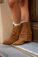 Botas de caña media confeccionadas en gamuza color marrón, con diseño slouchy y cierre lateral. Presentan una silueta de punta fina y taco cuña oculto.