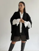 Ruana de tejido de punto trenzado en color crudo, con diseño abierto, corte holgado y mangas amplias tipo kimono.