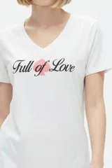 Remera negra de algodón, con cuello en V, mangas cortas, corte al cuerpo y estampa frontal con la frase "Emotionally Unavailable" en letras rosadas.